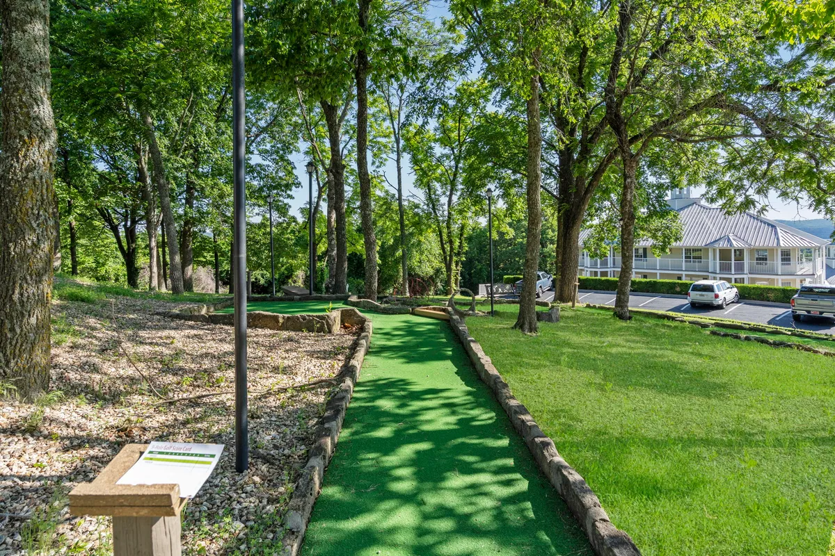 An inviting view of the mini-golf pathway, featuring winding stone trails, lush trees, and clear signage, creating a relaxed yet engaging environment perfect for group competitions or family outings.