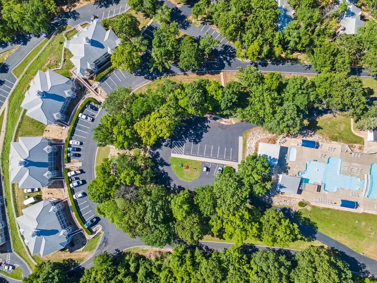 A lively exterior image of the resort’s swimming pool, ringed by trees, with residential buildings in the background. The scene suggests a communal, welcoming atmosphere—ideal for both relaxation and social activities.