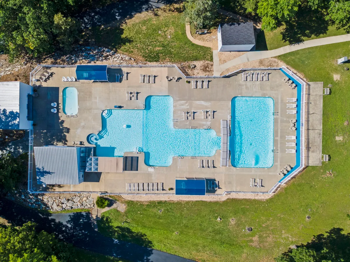 A sparkling outdoor swimming pool is the focal point here, surrounded by lounge chairs and lush greenery. The scene captures a relaxed, sun-soaked atmosphere, highlighting the pool as a central spot for swimming, sunbathing, and socializing in the fresh air.