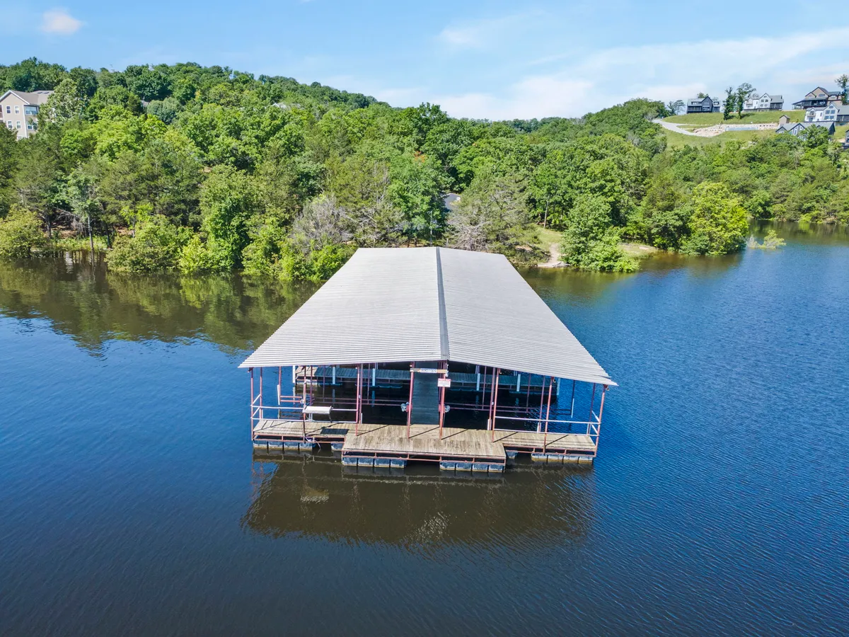 A peaceful scene with a boathouse on the water, surrounded by greenery and calm reflections, suggesting tranquil mornings and wildlife spotting.