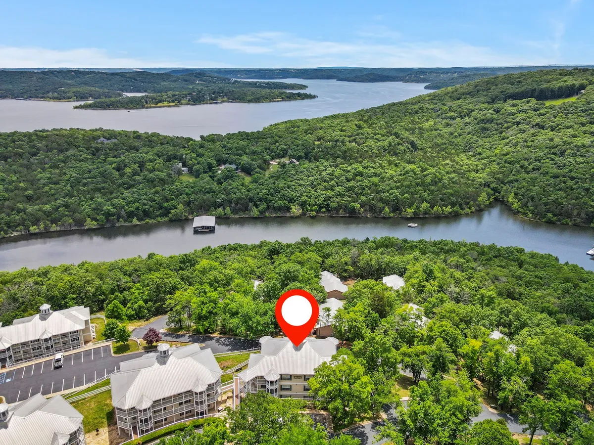 This image offers a tranquil view of lush greenery surrounding a lake, with residential buildings and winding roadways visible. The scenic outdoors invites visitors to imagine exploring nature, walking trails, or relaxing by the waterfront.