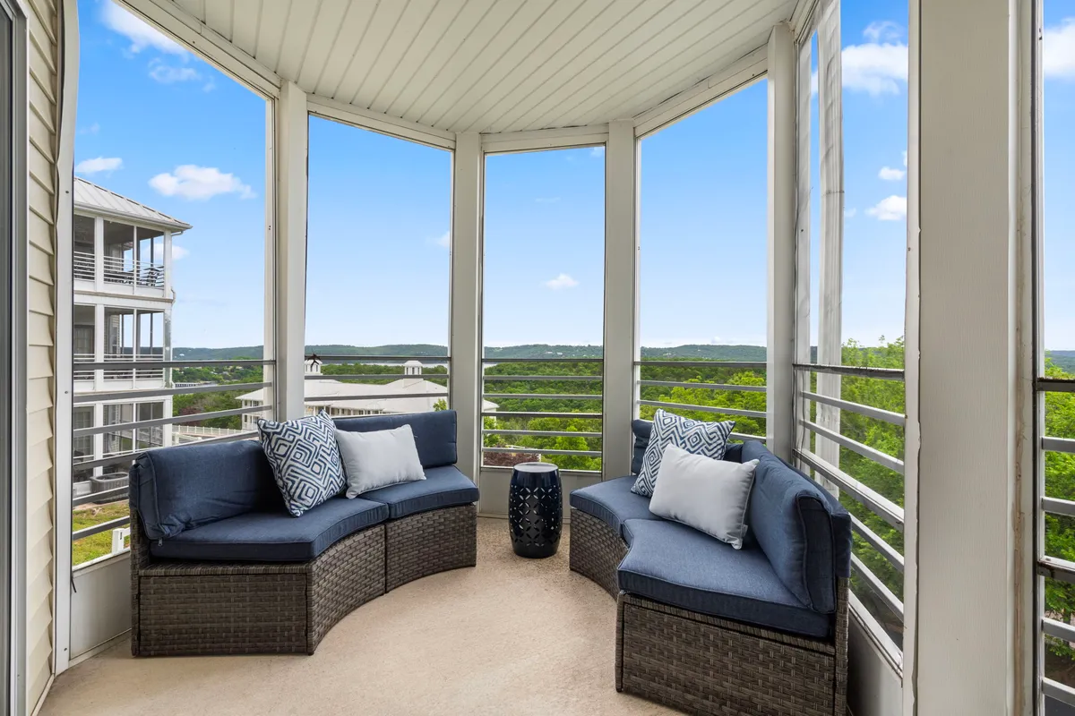 An inviting interior space featuring a curved seating arrangement positioned near panoramic windows that frame lush green landscapes. The view through the windows captures the natural beauty outside, suggesting an immersive connection with the outdoors.